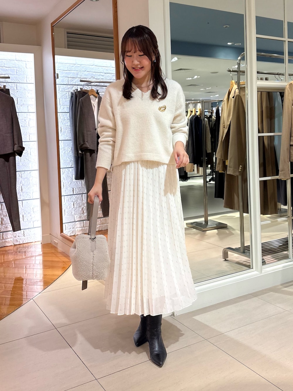 ホワイト系のスカート、ベージュ系のショルダーバッグ、ブルー系のニット/セーターを着用したレディースの冬コーディネートの2枚目の写真