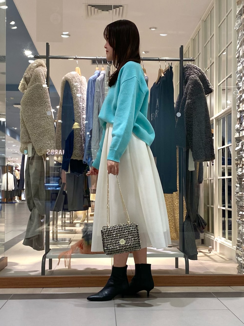 ホワイト系のスカート、グリーン系のニット/セーター、その他のショルダーバッグを着用したレディースの冬コーディネートの2枚目の写真