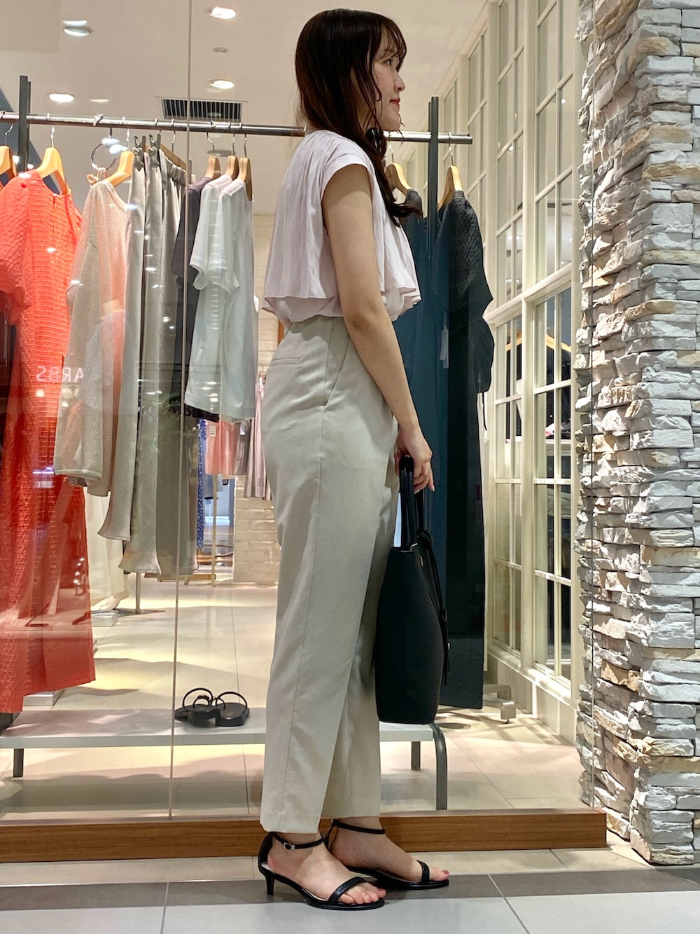 ブラック系のトートバッグ、シルバー系のサンダル、ベージュ系のその他パンツを着用したレディースの春コーディネートの2枚目の写真