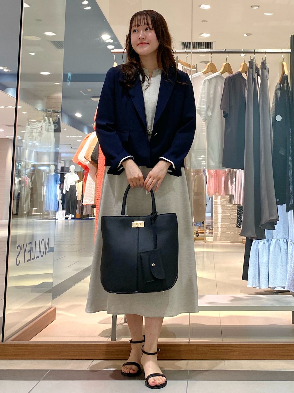 ブラック系のトートバッグ、ベージュ系のテーラードジャケット、オレンジ系のワンピースを着用したレディースの春コーディネートの2枚目の写真