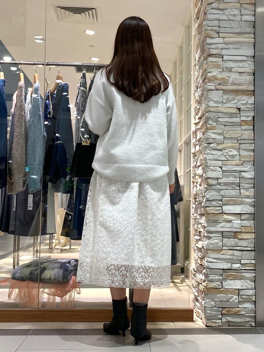 ブラック系のショルダーバッグ、ホワイト系のニット/セーター、ホワイト系のスカートを着用したレディースの冬コーディネートの3枚目の写真