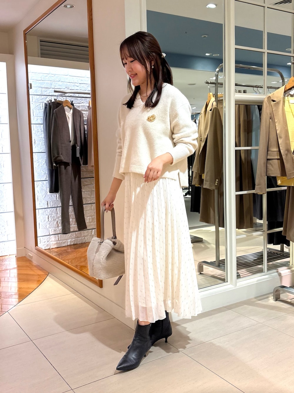 ホワイト系のスカート、ベージュ系のショルダーバッグ、ブルー系のニット/セーターを着用したレディースの冬コーディネートの4枚目の写真