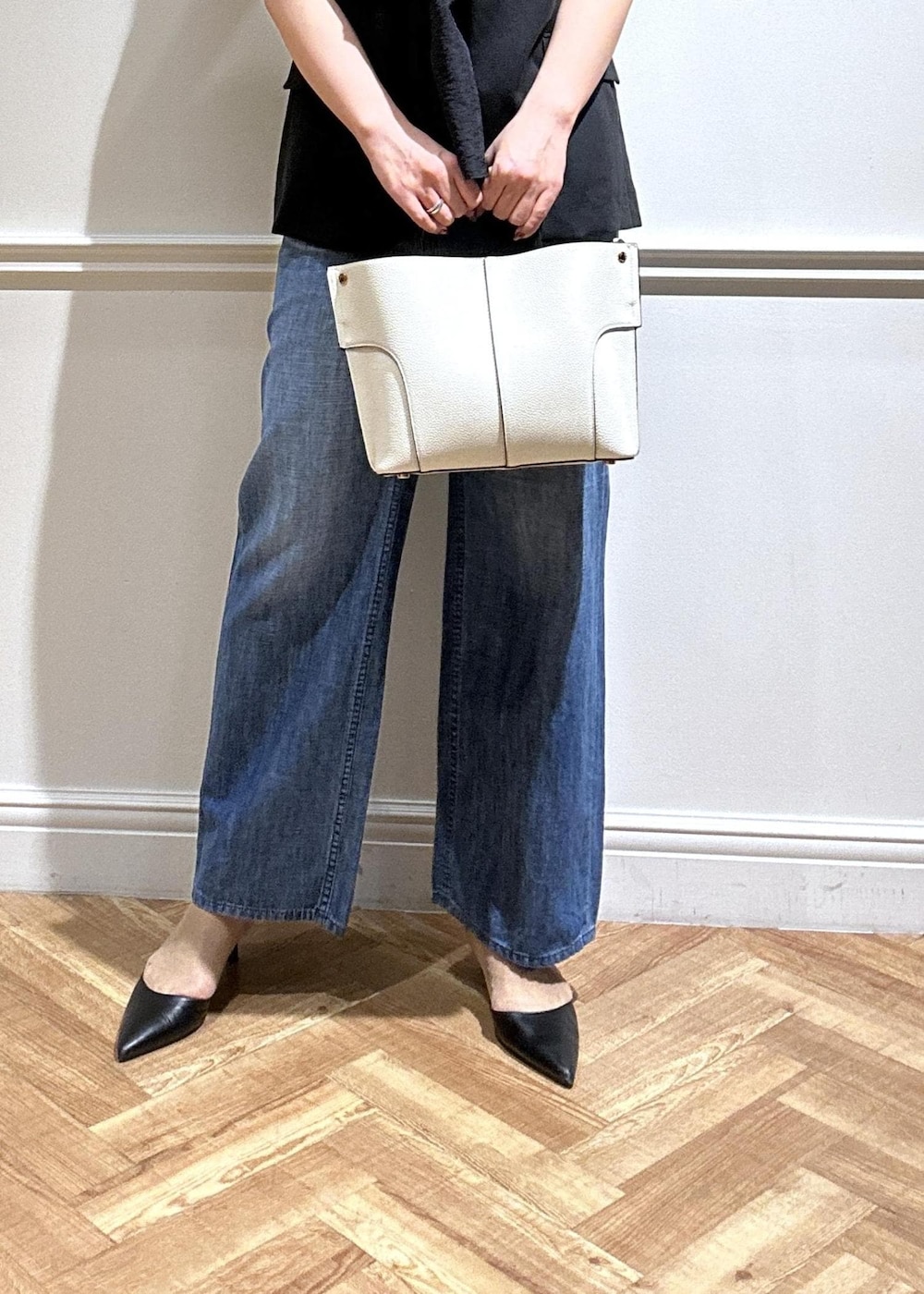 ブラック系のテーラードジャケット、ブルー系のデニムパンツ、ホワイト系のハンドバッグを着用したレディースの夏コーディネートの5枚目の写真