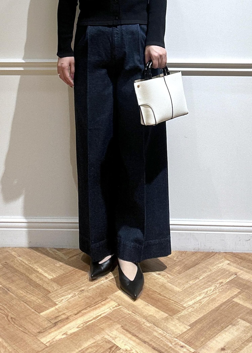 ホワイト系のハンドバッグ、ブルー系のデニムパンツ、ブラック系のカーディガン/ボレロを着用したレディースの春コーディネートの5枚目の写真