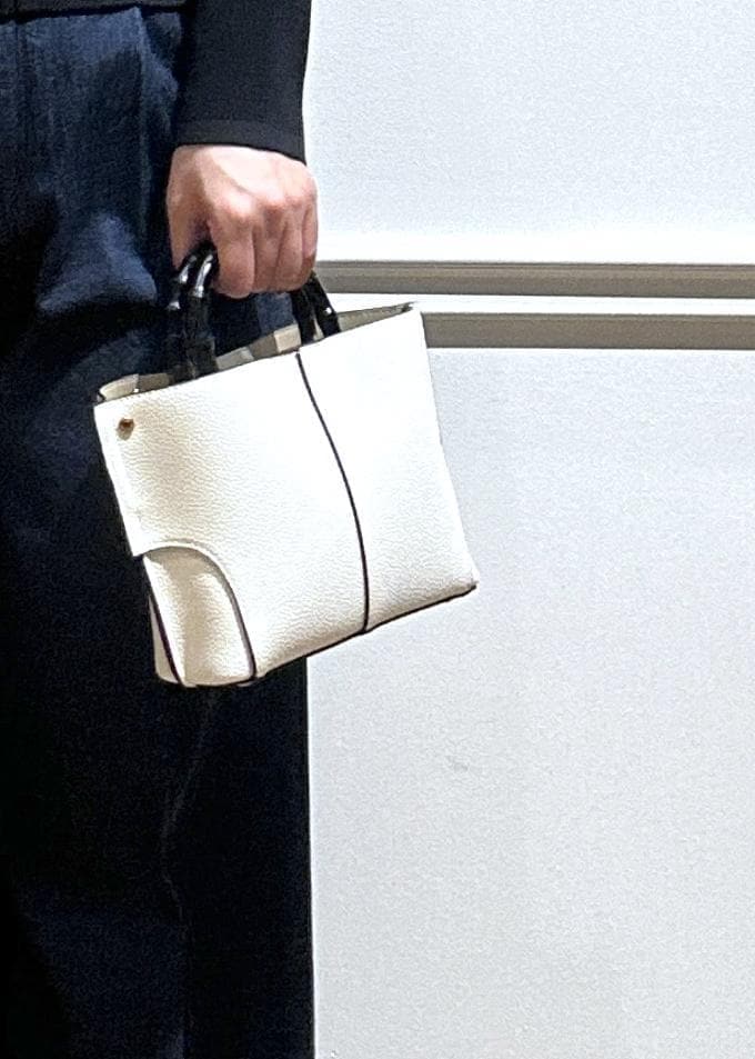 ホワイト系のハンドバッグ、ブルー系のデニムパンツ、ブラック系のカーディガン/ボレロを着用したレディースの春コーディネートの7枚目の写真