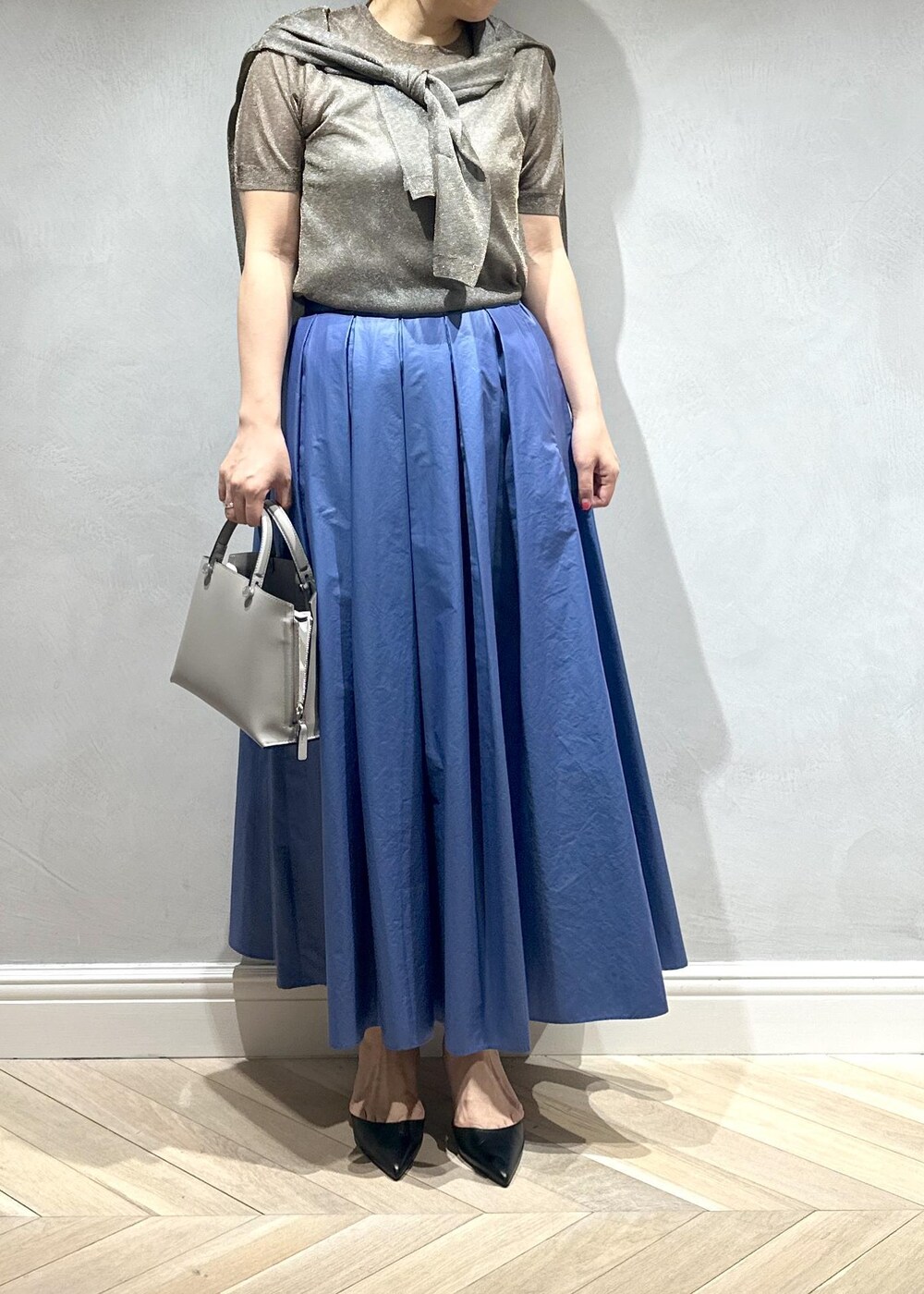 グレー系のハンドバッグ、ベージュ系のキャミソール、ブラウン系のニット/セーターを着用したレディースの夏コーディネートの2枚目の写真