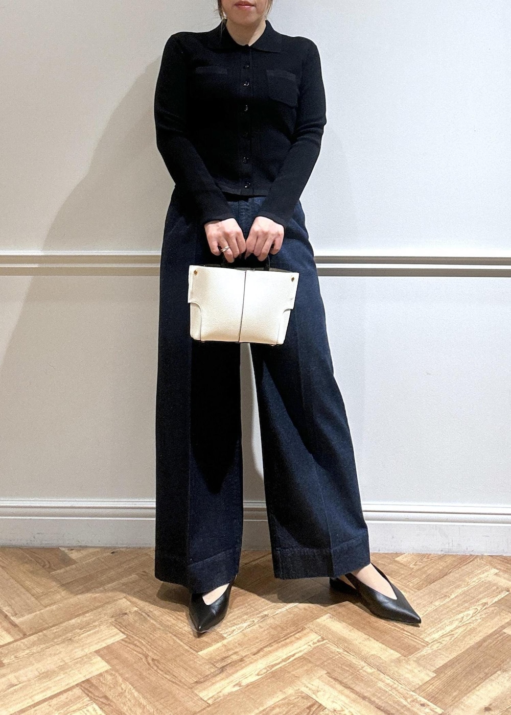 ホワイト系のハンドバッグ、ブルー系のデニムパンツ、ブラック系のカーディガン/ボレロを着用したレディースの春コーディネートの2枚目の写真