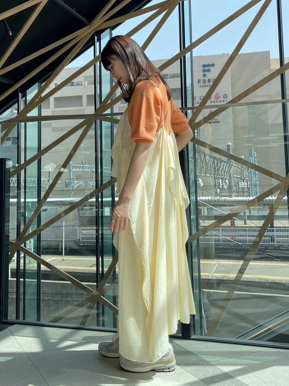 ホワイト系のワンピース、オレンジ系のニット/セーター、シルバー系のネックレスを着用したレディースの春コーディネートの3枚目の写真