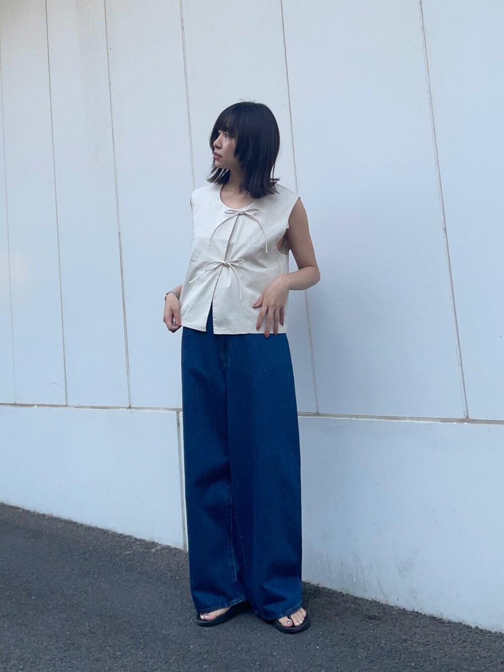 グレー系のベスト、ブルー系のデニムパンツを着用したレディースの春コーディネートの2枚目の写真