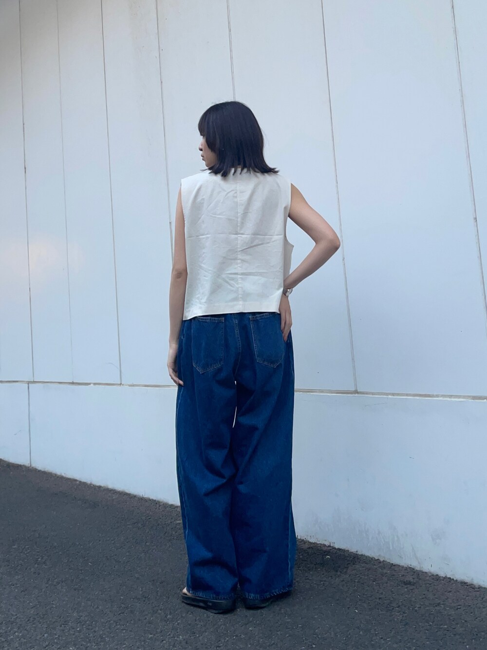 グレー系のベスト、ブルー系のデニムパンツを着用したレディースの春コーディネートの4枚目の写真