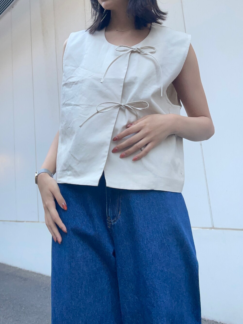 グレー系のベスト、ブルー系のデニムパンツを着用したレディースの春コーディネートの5枚目の写真