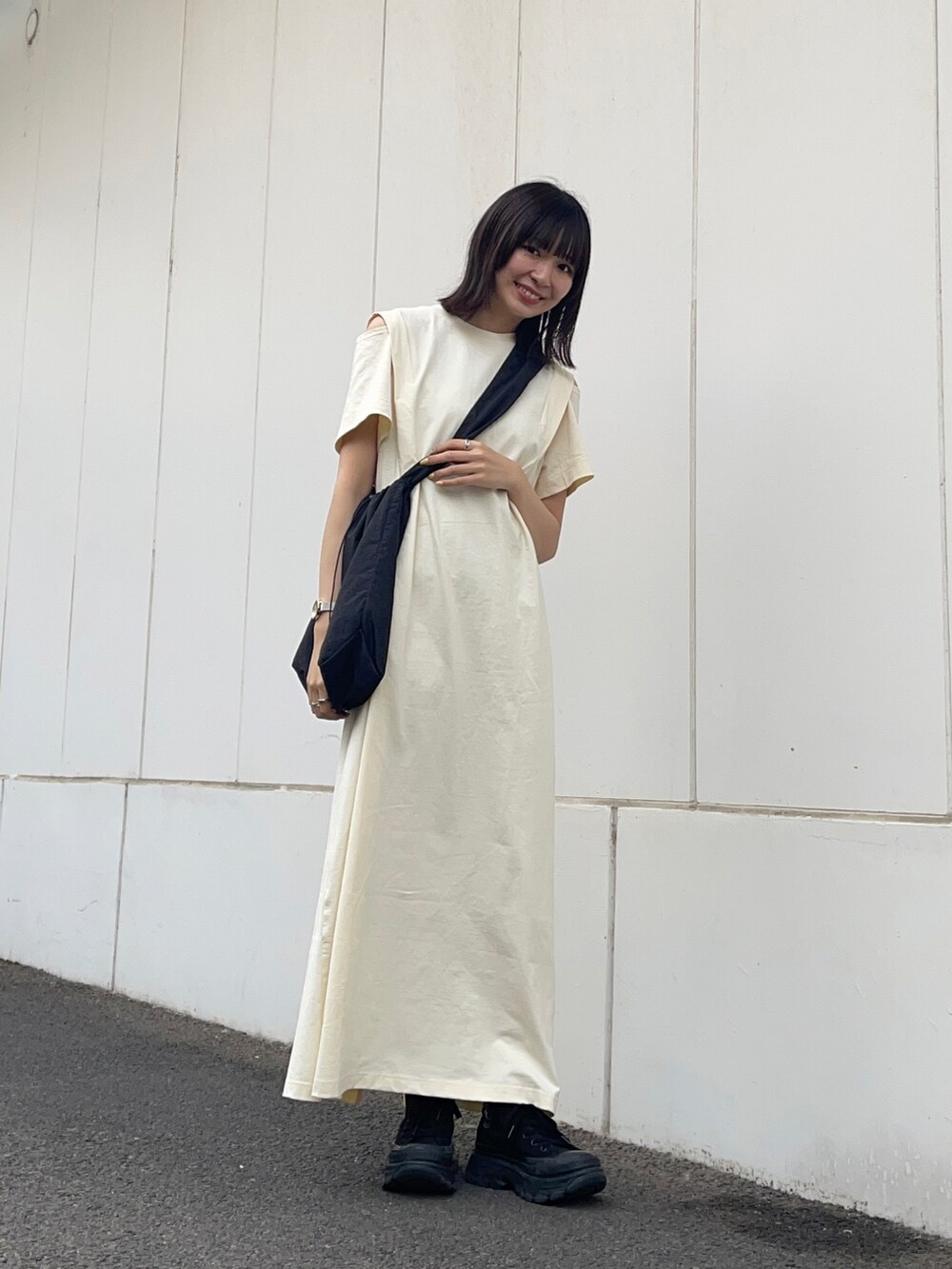 ブラック系のショルダーバッグ、ホワイト系のワンピースを着用したレディースの夏コーディネートの2枚目の写真
