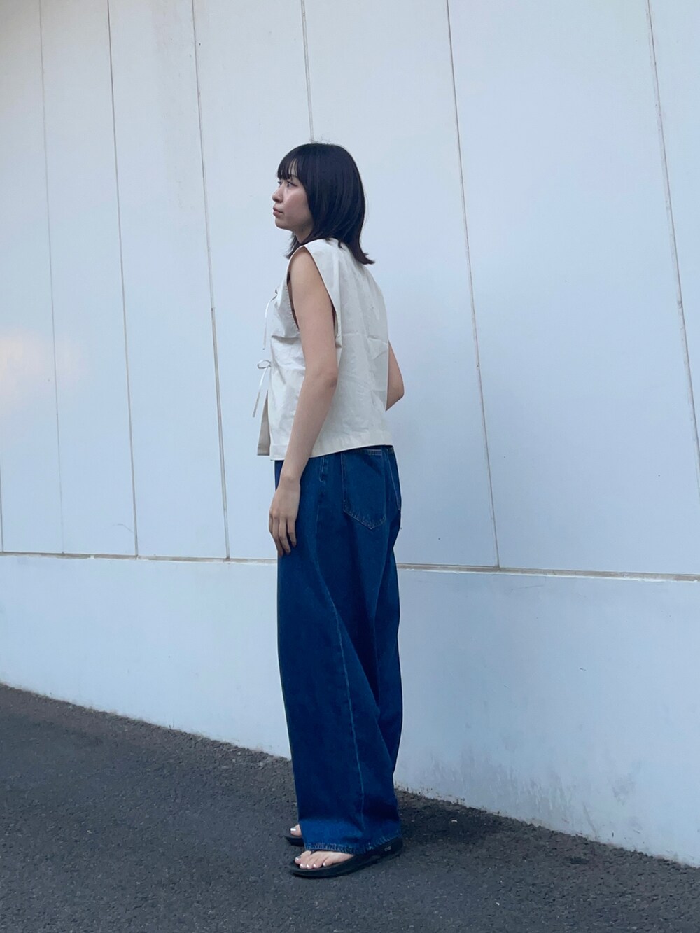 グレー系のベスト、ブルー系のデニムパンツを着用したレディースの春コーディネートの3枚目の写真