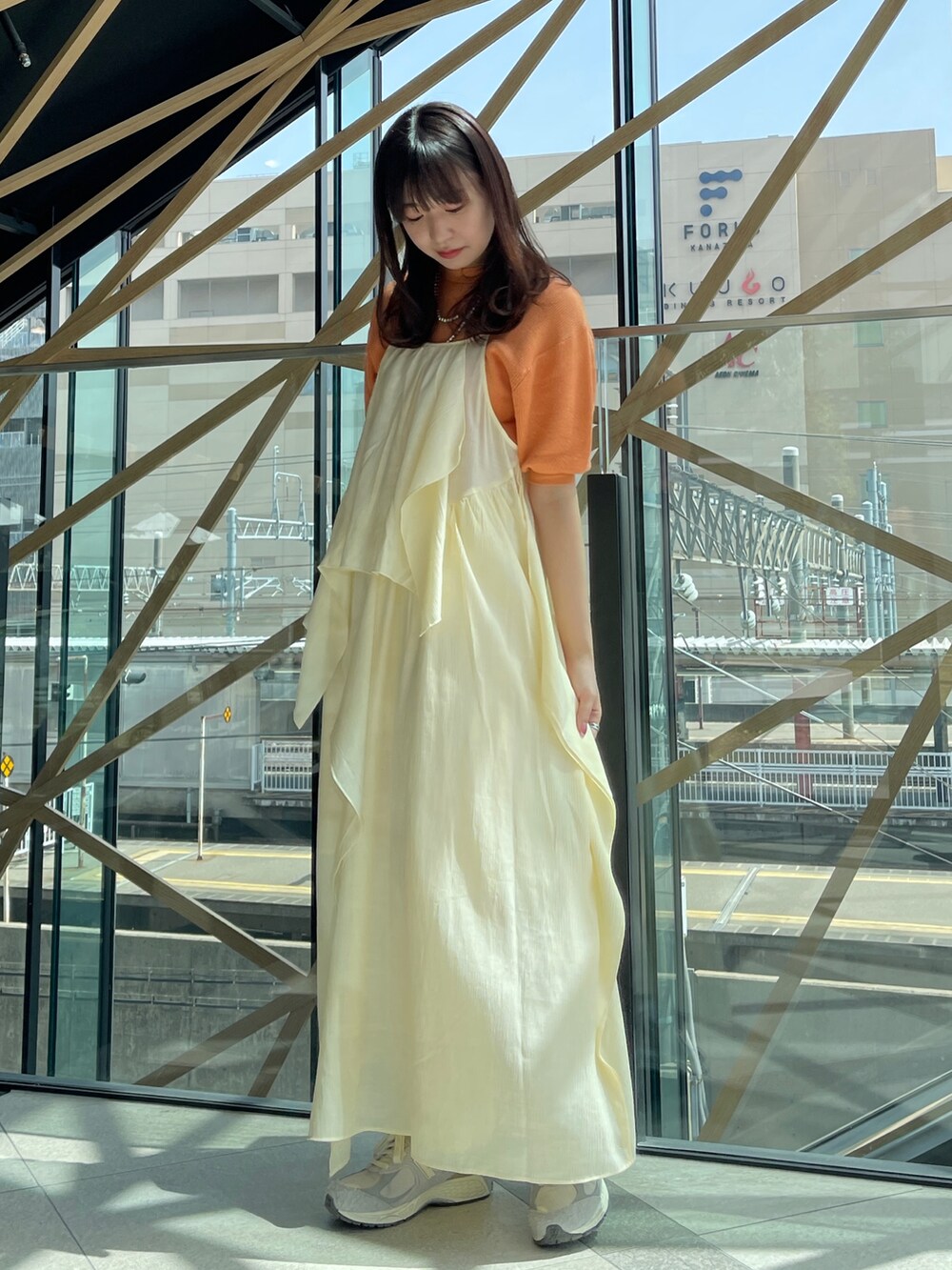 ホワイト系のワンピース、オレンジ系のニット/セーター、シルバー系のネックレスを着用したレディースの春コーディネートの2枚目の写真