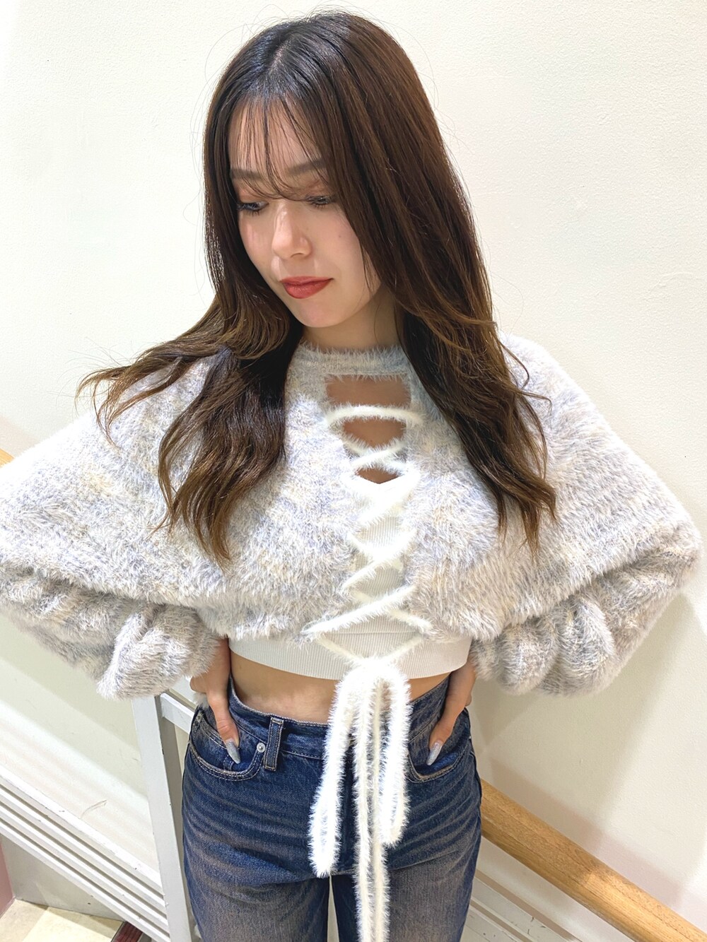 ホワイト系のニット/セーター、ホワイト系のキャミソール、ブルー系のデニムパンツを着用したレディースの秋コーディネートの3枚目の写真