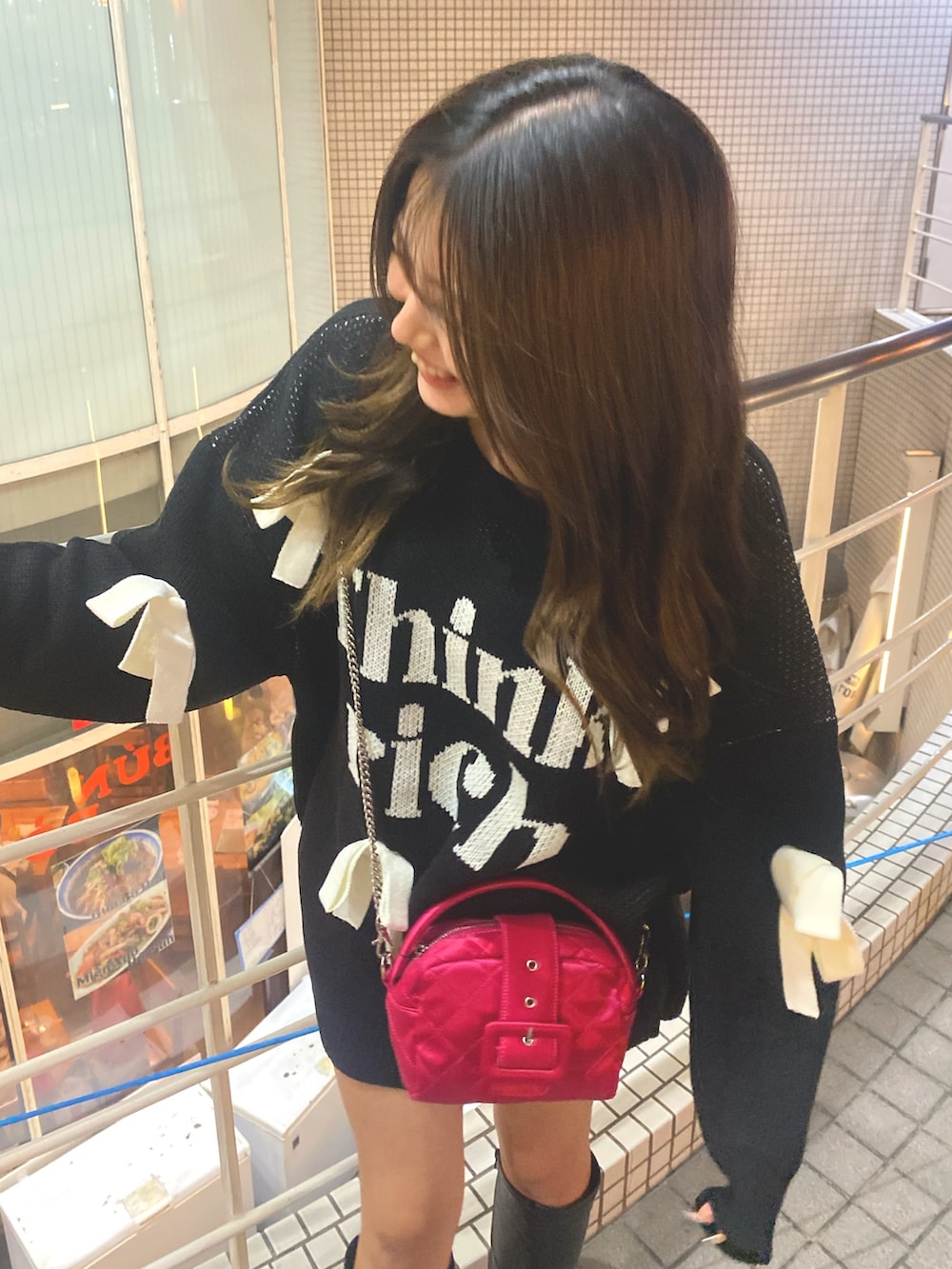 ブラック系のニット/セーター、ピンク系のショルダーバッグ、ブラック系のブーツを着用したレディースの冬コーディネートの2枚目の写真