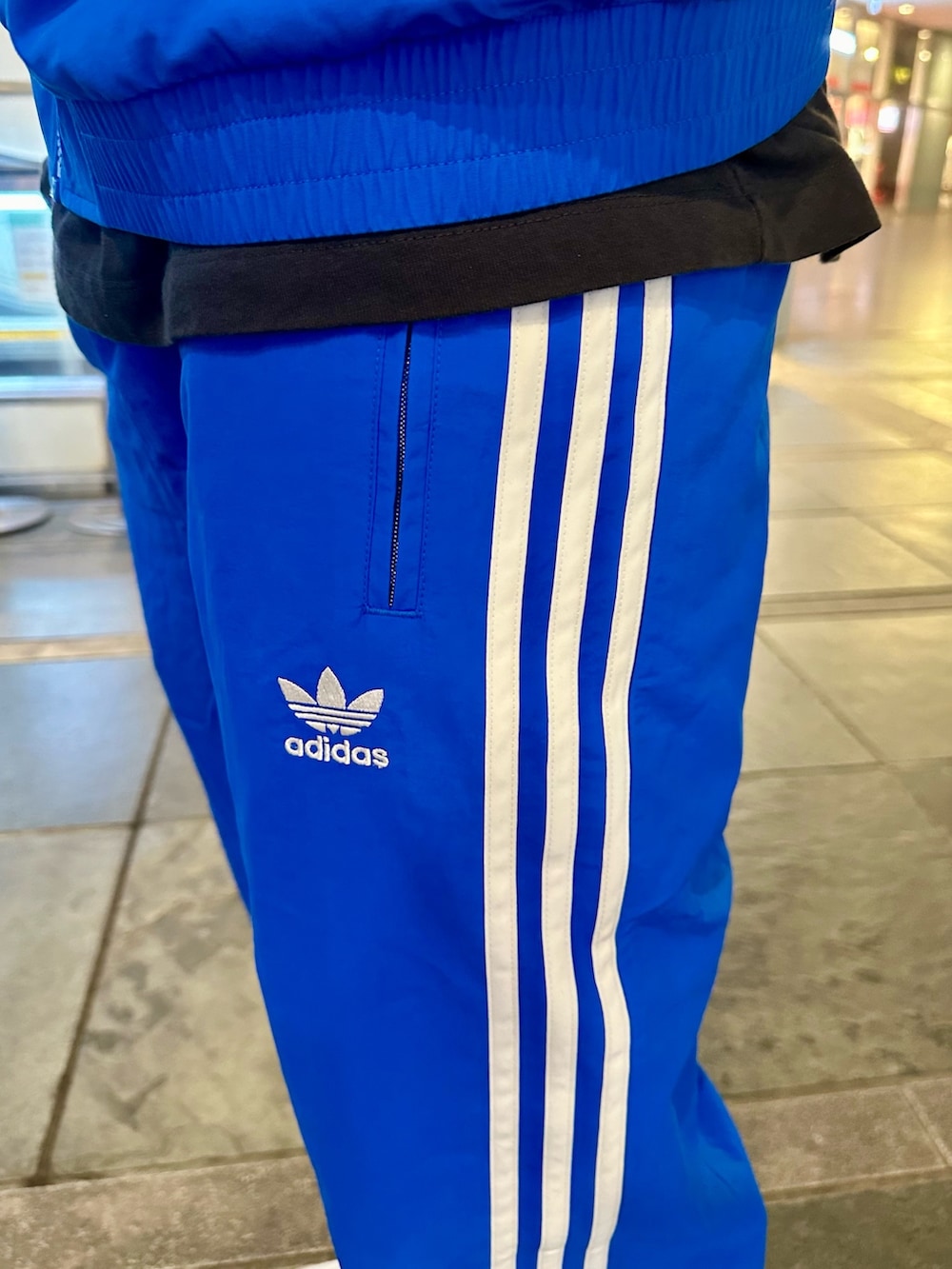 ブルー系のナイロンジャケット、ブルー系のその他パンツ、ホワイト系のシューズを着用したメンズの春コーディネートの4枚目の写真