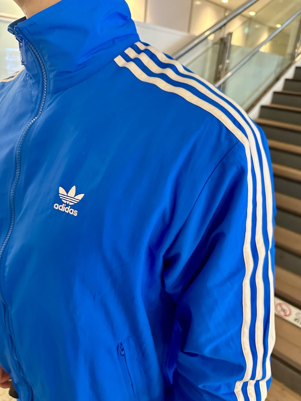 ブルー系のナイロンジャケット、ブルー系のその他パンツ、ホワイト系のシューズを着用したメンズの春コーディネートの3枚目の写真