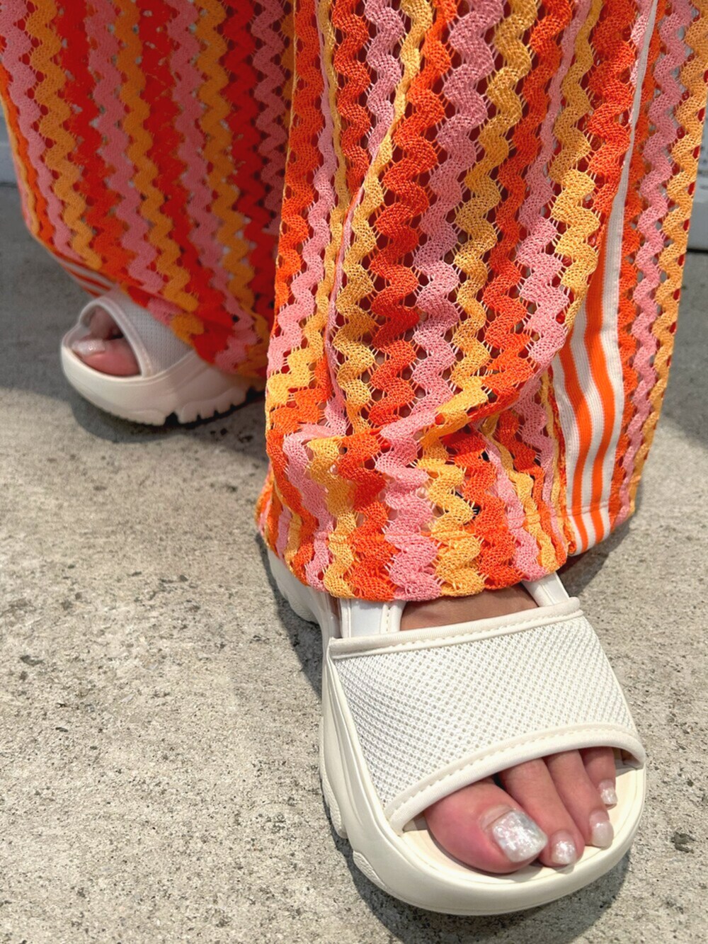 シルバー系のハンドバッグ、ピンク系のTシャツ/カットソー、ホワイト系のスカートを着用したレディースの春コーディネートの4枚目の写真