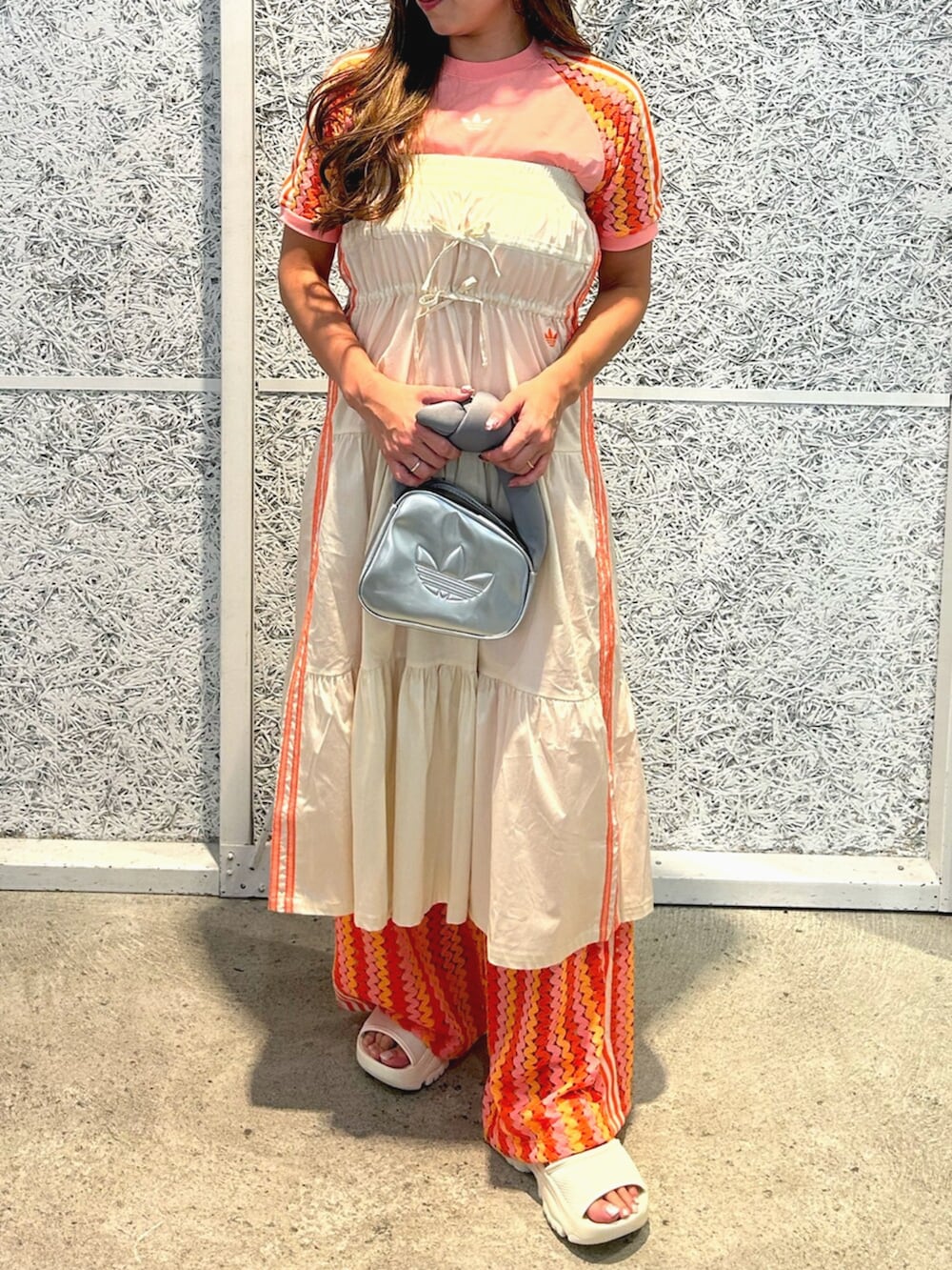 シルバー系のハンドバッグ、ピンク系のTシャツ/カットソー、ホワイト系のスカートを着用したレディースの春コーディネートの2枚目の写真