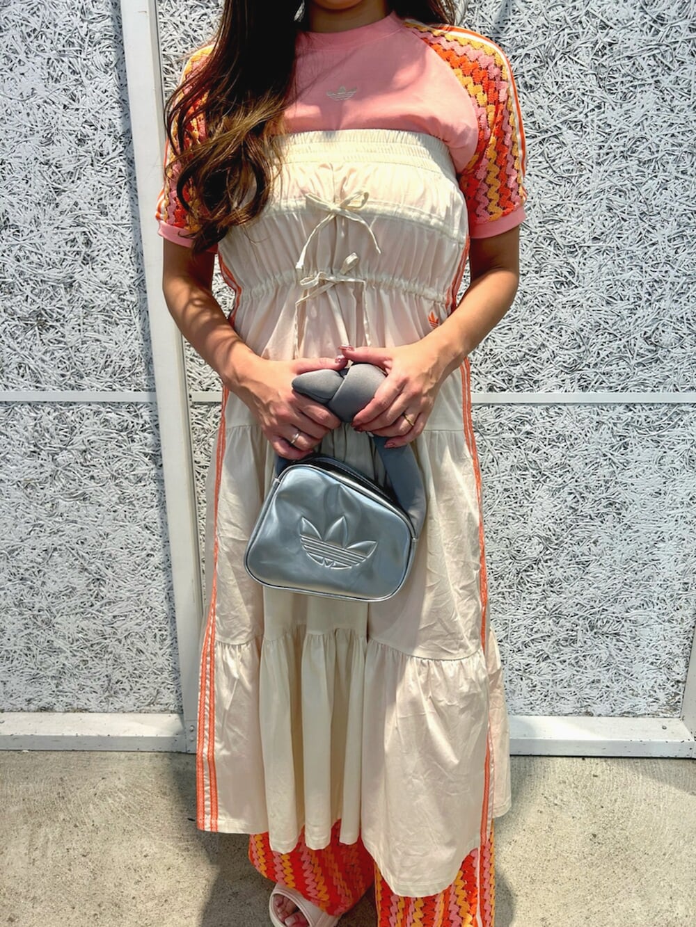 シルバー系のハンドバッグ、ピンク系のTシャツ/カットソー、ホワイト系のスカートを着用したレディースの春コーディネートの3枚目の写真