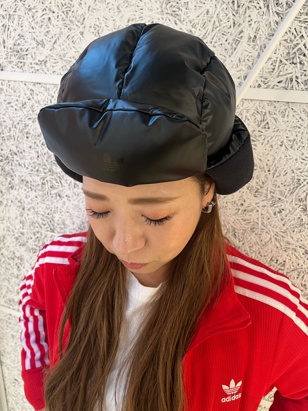 レッド系のジャージ、ブラック系のスニーカー、ブラック系のハットを着用したレディースの秋コーディネートの3枚目の写真