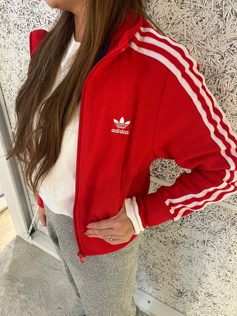 レッド系のジャージ、ブラック系のスニーカー、ブラック系のハットを着用したレディースの秋コーディネートの2枚目の写真