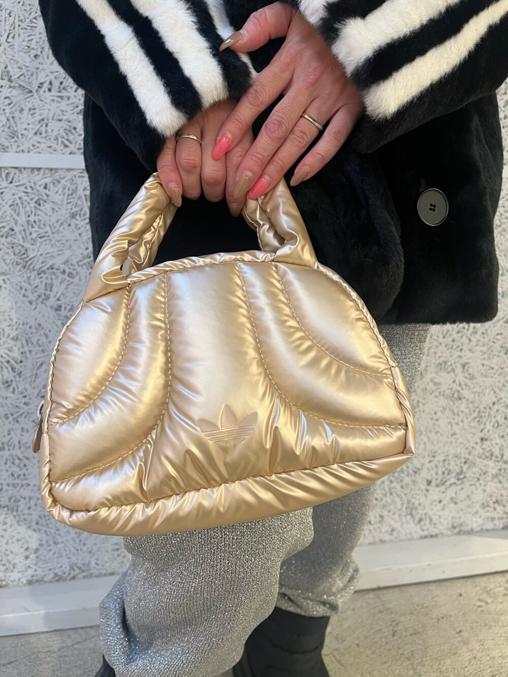 ブラック系のスニーカー、ブラック系のナイロンジャケット、ゴールド系のハンドバッグを着用したレディースの秋コーディネートの3枚目の写真