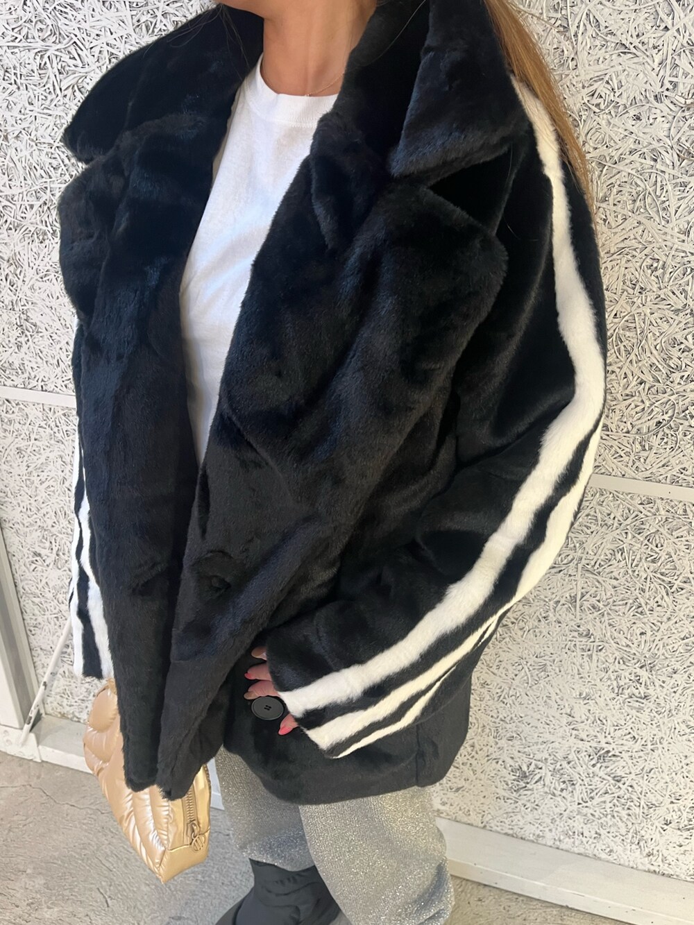 ブラック系のスニーカー、ブラック系のナイロンジャケット、ゴールド系のハンドバッグを着用したレディースの秋コーディネートの2枚目の写真