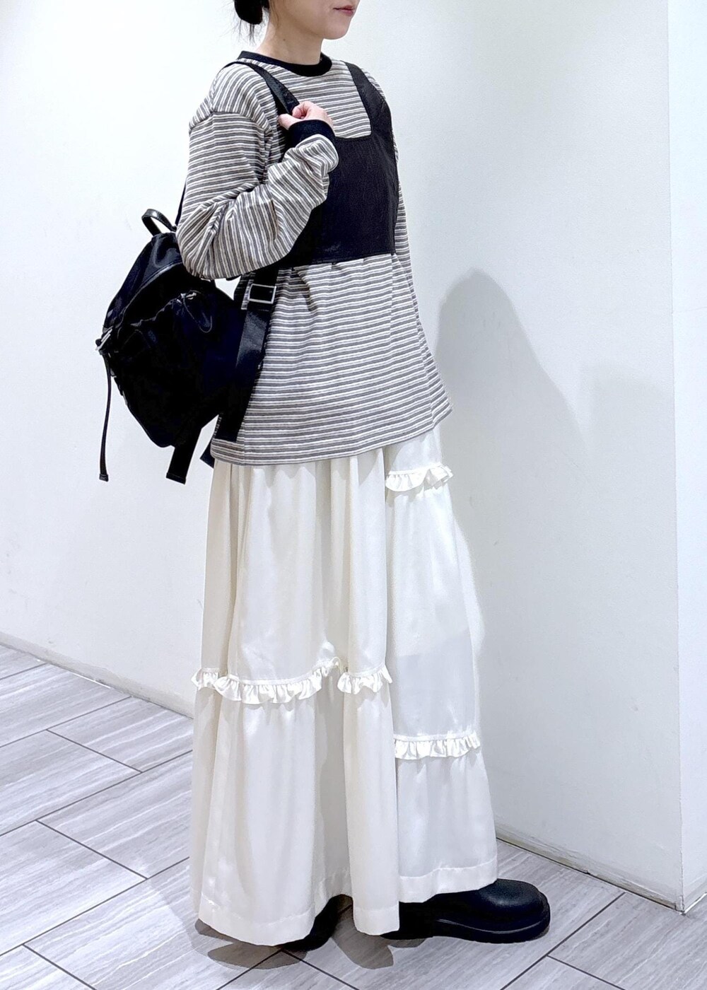 ブラック系のブーツ、ホワイト系のスカート、ホワイト系のTシャツ/カットソーを着用したレディースの冬コーディネートの2枚目の写真