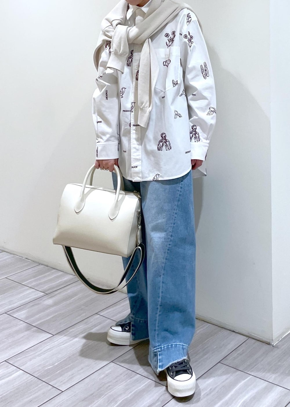 ブルー系のデニムパンツ、ホワイト系のボストンバッグ、ベージュ系のカーディガン/ボレロを着用したレディースの冬コーディネートの2枚目の写真