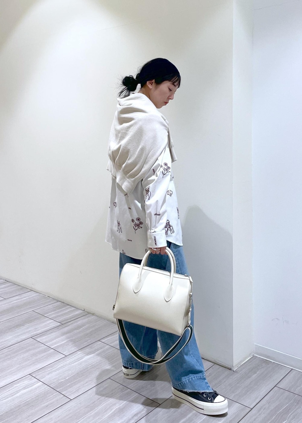 ブルー系のデニムパンツ、ホワイト系のボストンバッグ、ベージュ系のカーディガン/ボレロを着用したレディースの冬コーディネートの3枚目の写真