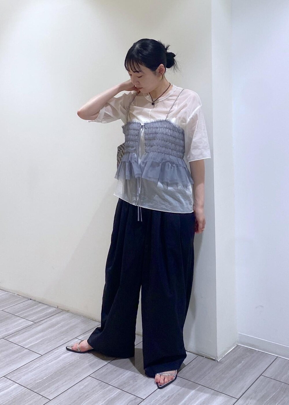 シルバー系のハンドバッグ、シルバー系のサンダル、ホワイト系のTシャツ/カットソーを着用したレディースの夏コーディネートの2枚目の写真