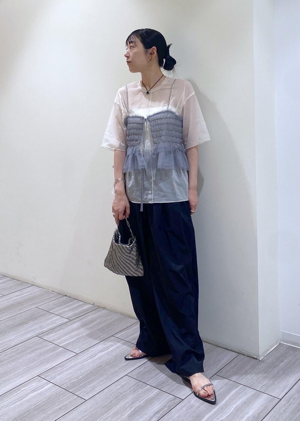 シルバー系のハンドバッグ、シルバー系のサンダル、ホワイト系のTシャツ/カットソーを着用したレディースの夏コーディネートの4枚目の写真