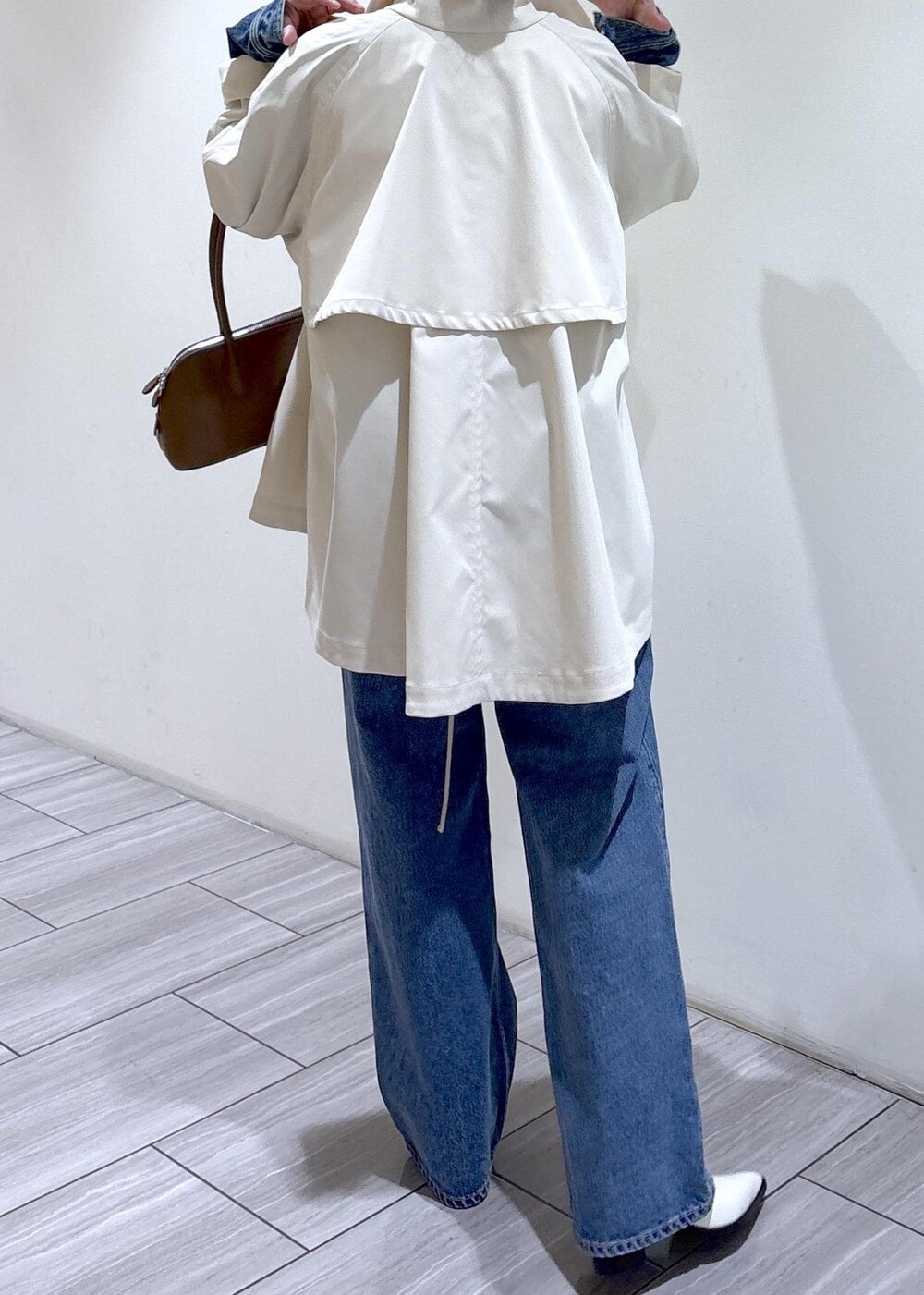 ホワイト系のパンプス、ブラウン系のボストンバッグ、ホワイト系のトレンチコートを着用したレディースの冬コーディネートの5枚目の写真