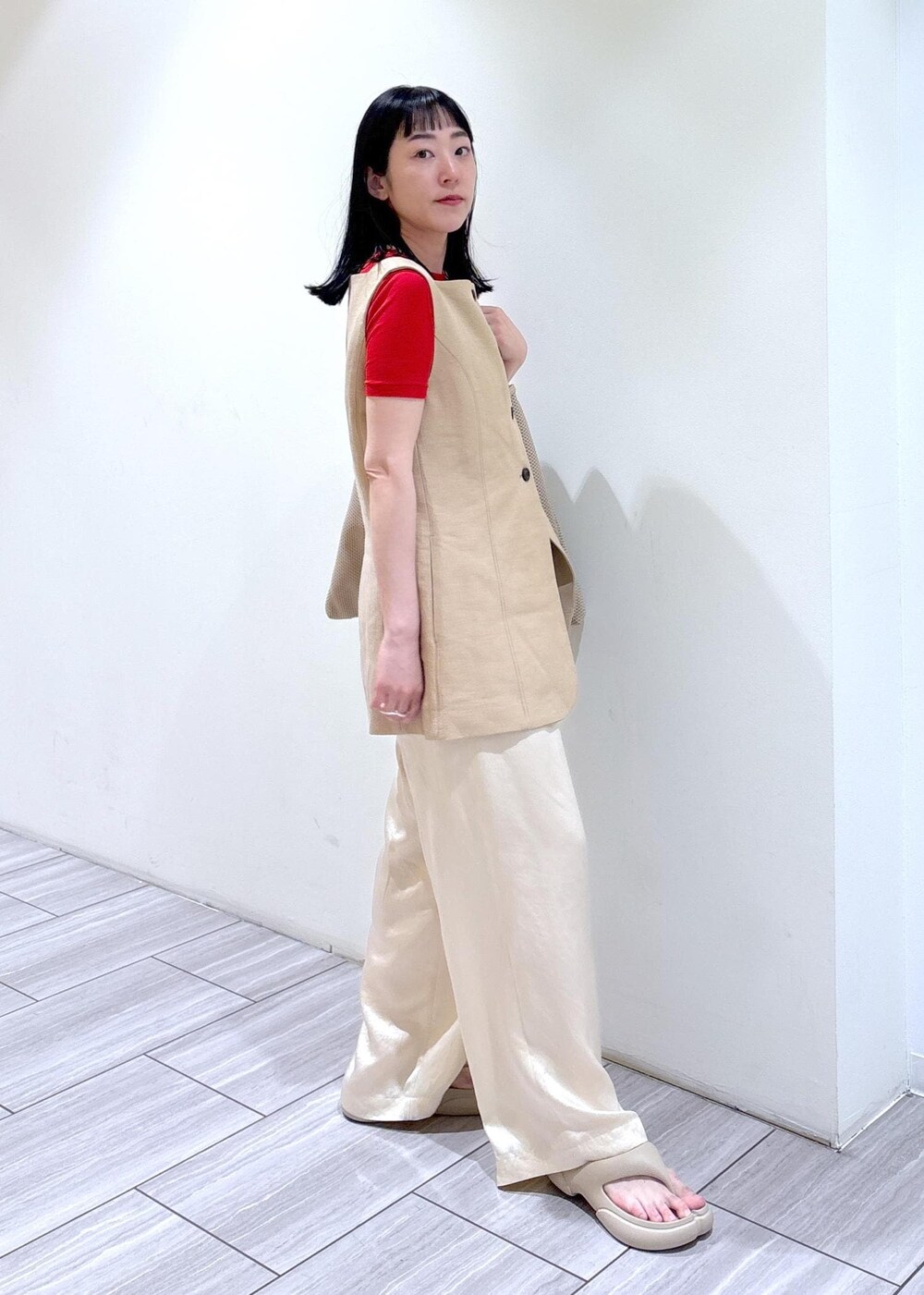 ベージュ系のショルダーバッグ、ホワイト系のスラックス、ベージュ系のベストを着用したレディースの春コーディネートの2枚目の写真