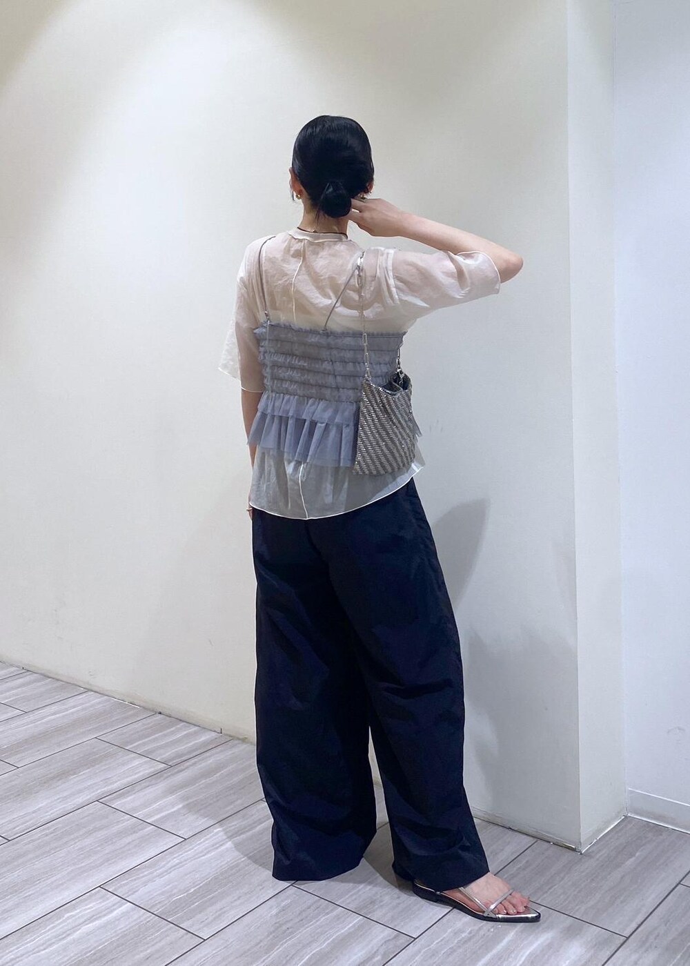 シルバー系のハンドバッグ、シルバー系のサンダル、ホワイト系のTシャツ/カットソーを着用したレディースの夏コーディネートの3枚目の写真