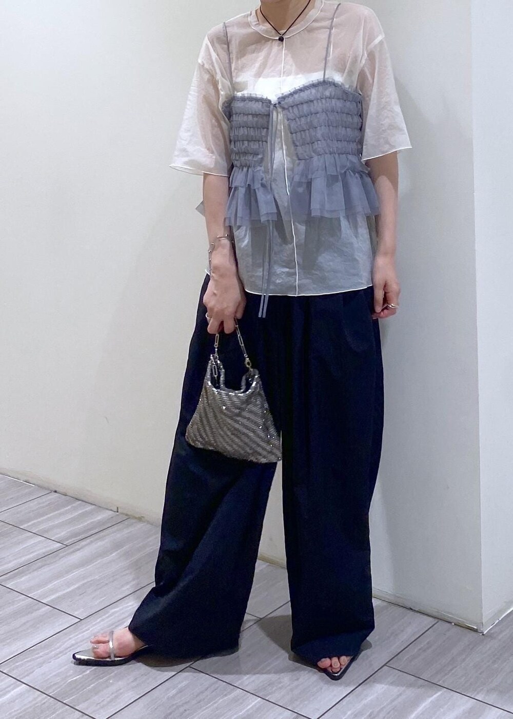 シルバー系のハンドバッグ、シルバー系のサンダル、ホワイト系のTシャツ/カットソーを着用したレディースの夏コーディネートの6枚目の写真