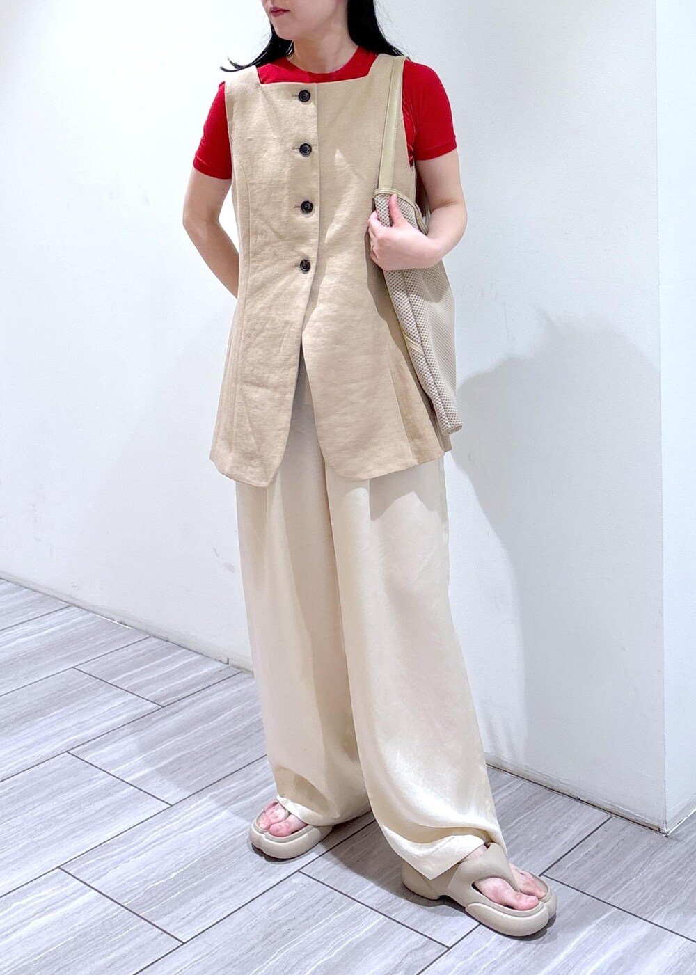 ベージュ系のショルダーバッグ、ホワイト系のスラックス、ベージュ系のベストを着用したレディースの春コーディネートの4枚目の写真