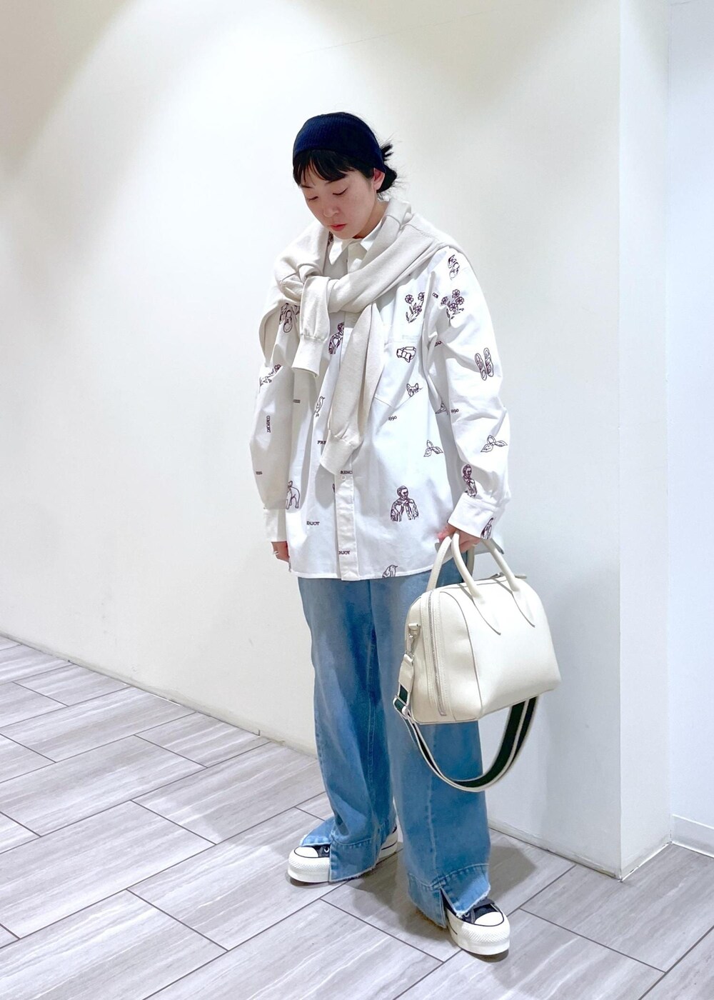 ブルー系のデニムパンツ、ホワイト系のボストンバッグ、ベージュ系のカーディガン/ボレロを着用したレディースの冬コーディネートの6枚目の写真