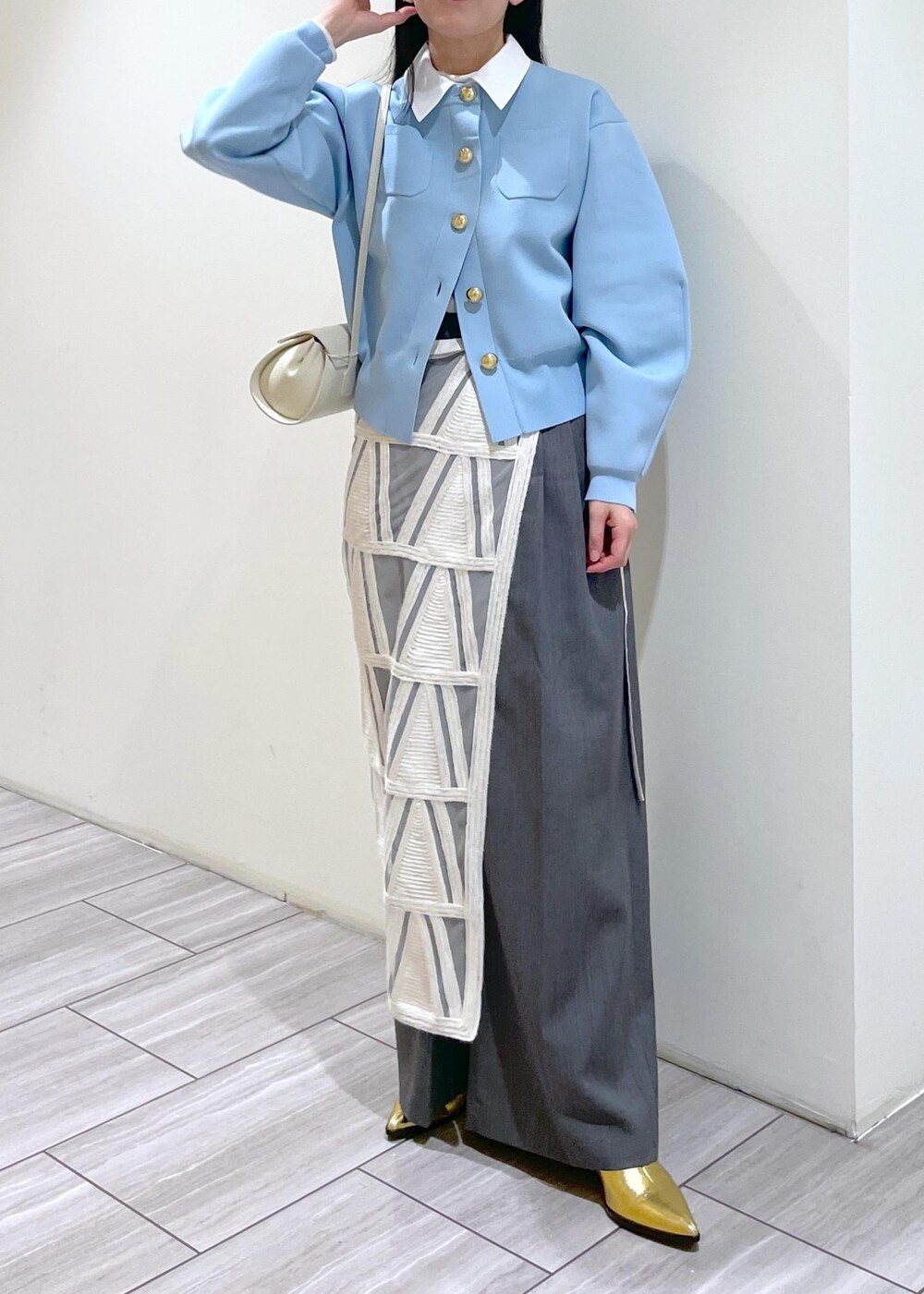 ゴールド系のブーツ、ホワイト系のショルダーバッグ、ホワイト系のスカートを着用したレディースの冬コーディネートの3枚目の写真