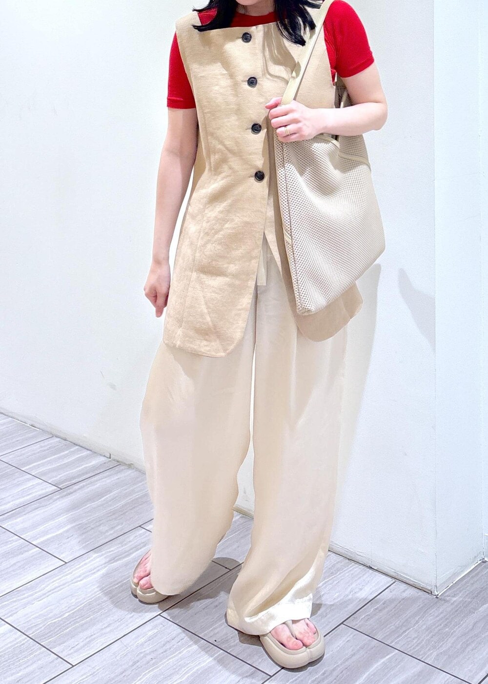 ベージュ系のショルダーバッグ、ホワイト系のスラックス、ベージュ系のベストを着用したレディースの春コーディネートの6枚目の写真