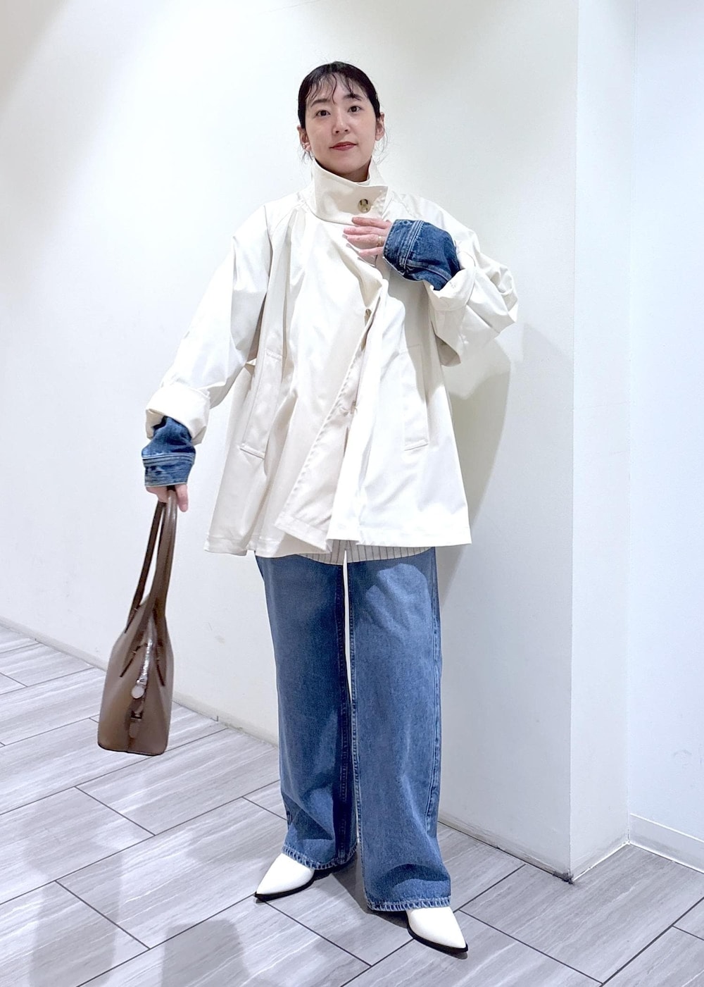 ホワイト系のパンプス、ブラウン系のボストンバッグ、ホワイト系のトレンチコートを着用したレディースの冬コーディネートの6枚目の写真