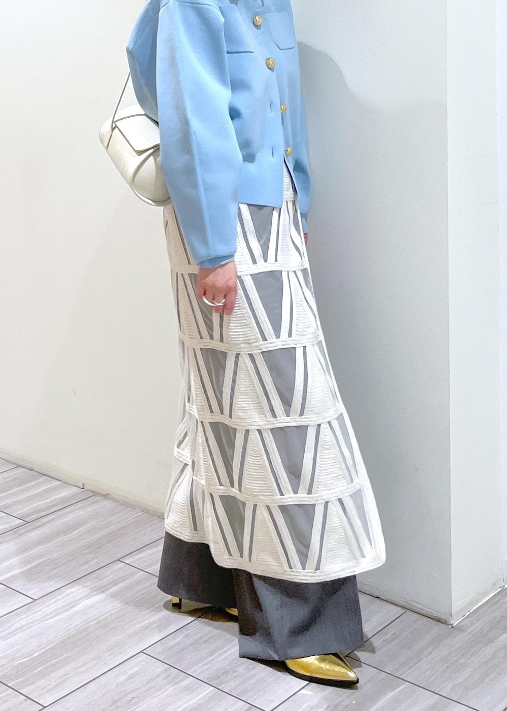 ゴールド系のブーツ、ホワイト系のショルダーバッグ、ホワイト系のスカートを着用したレディースの冬コーディネートの4枚目の写真