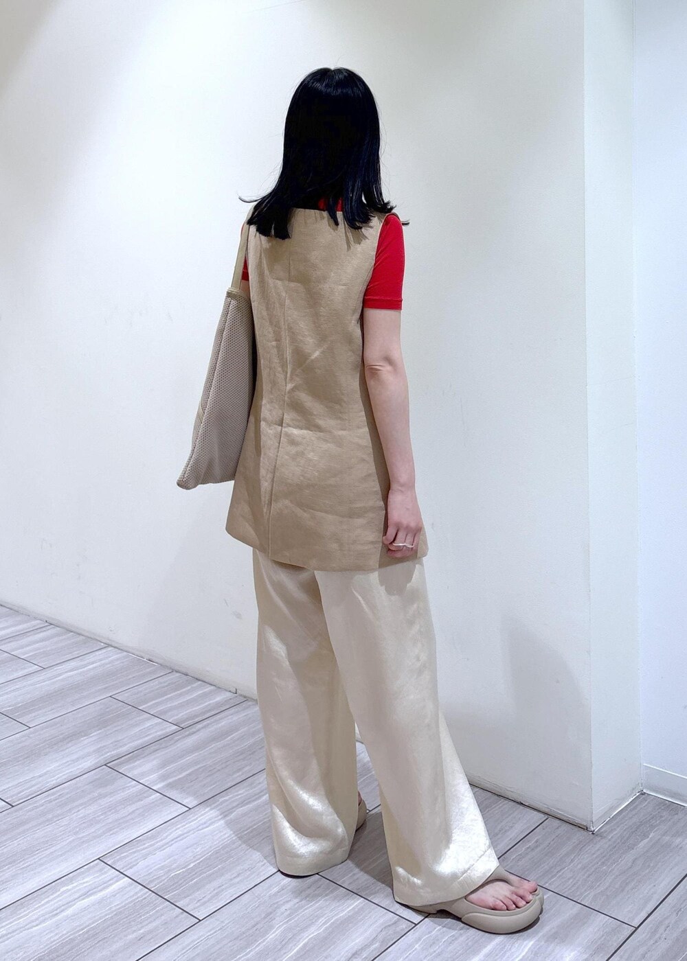 ベージュ系のショルダーバッグ、ホワイト系のスラックス、ベージュ系のベストを着用したレディースの春コーディネートの3枚目の写真