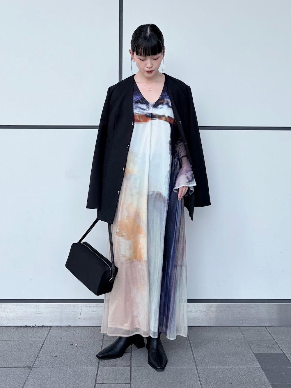 ブラック系のノーカラージャケット、ブラック系のドレス、ブラック系のハンドバッグを着用したレディースの冬コーディネートの2枚目の写真