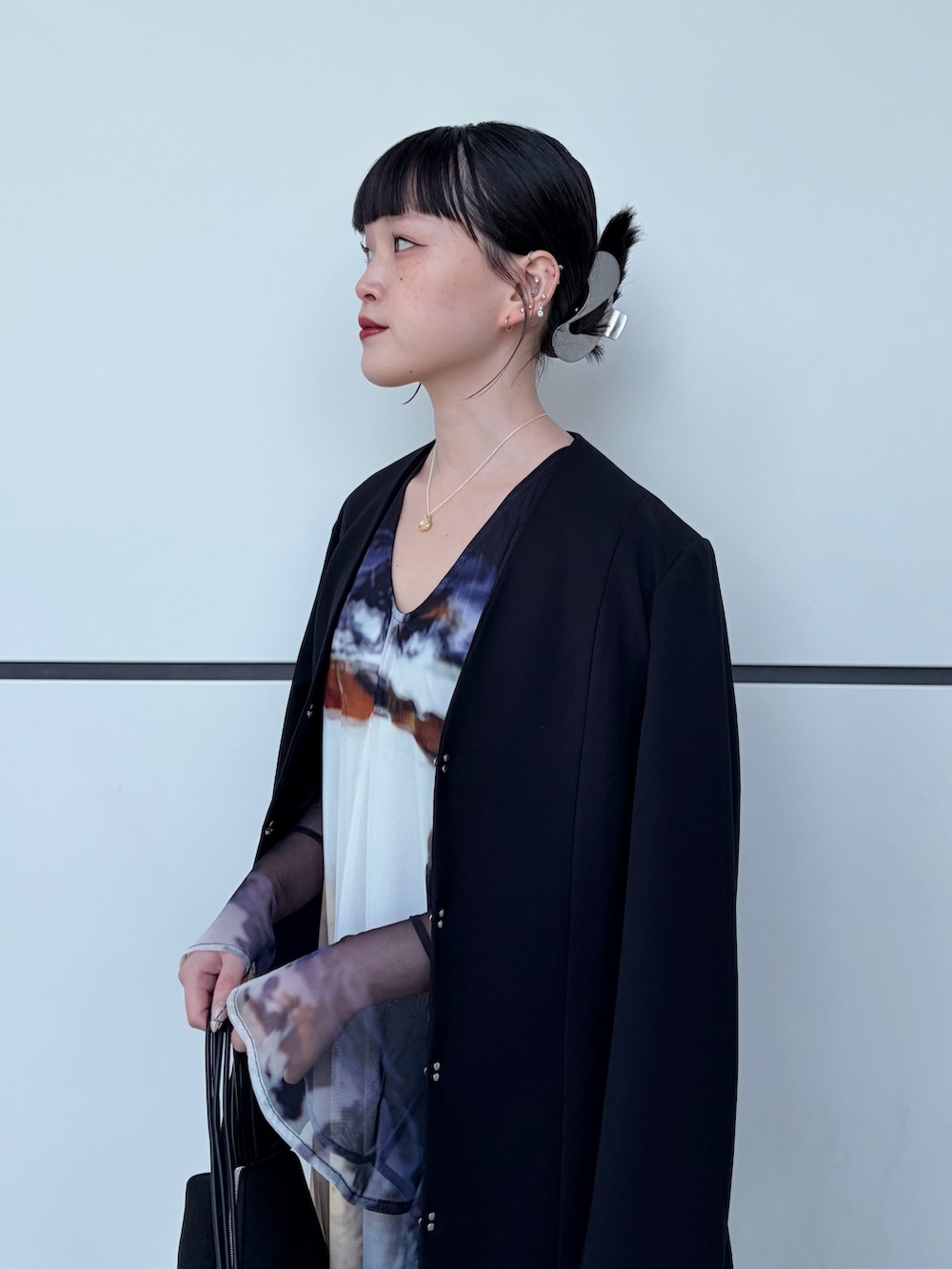 ブラック系のノーカラージャケット、ブラック系のドレス、ブラック系のハンドバッグを着用したレディースの冬コーディネートの3枚目の写真