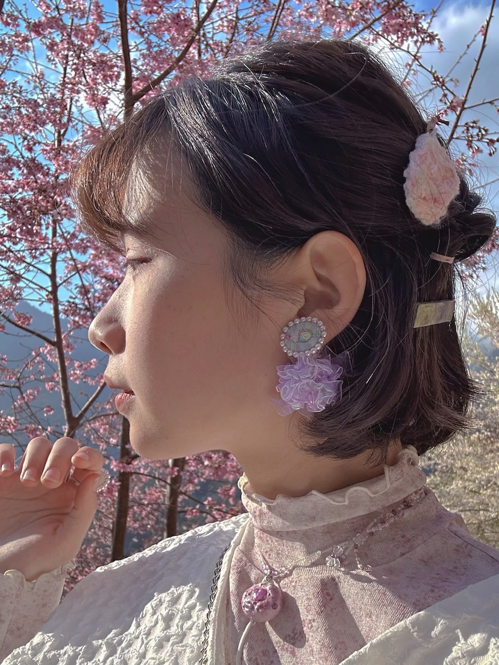 ピンク系のスニーカー、パープル系のワンピース、ホワイト系のブルゾンを着用したレディースの春コーディネートの2枚目の写真