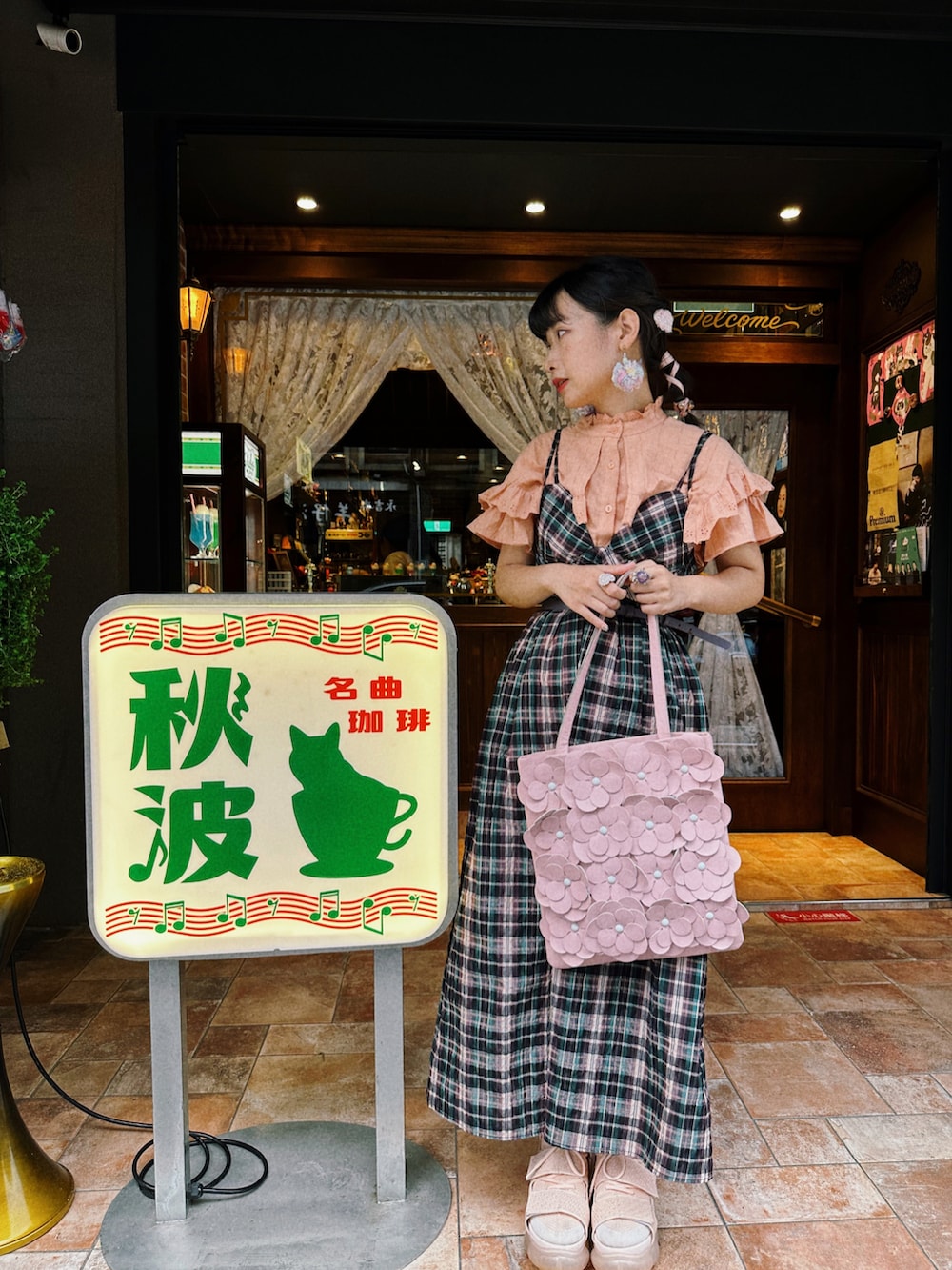 ピンク系のショルダーバッグ、パープル系のジャンパースカート、オレンジ系のシャツ/ブラウスを着用したレディースの夏コーディネートの2枚目の写真