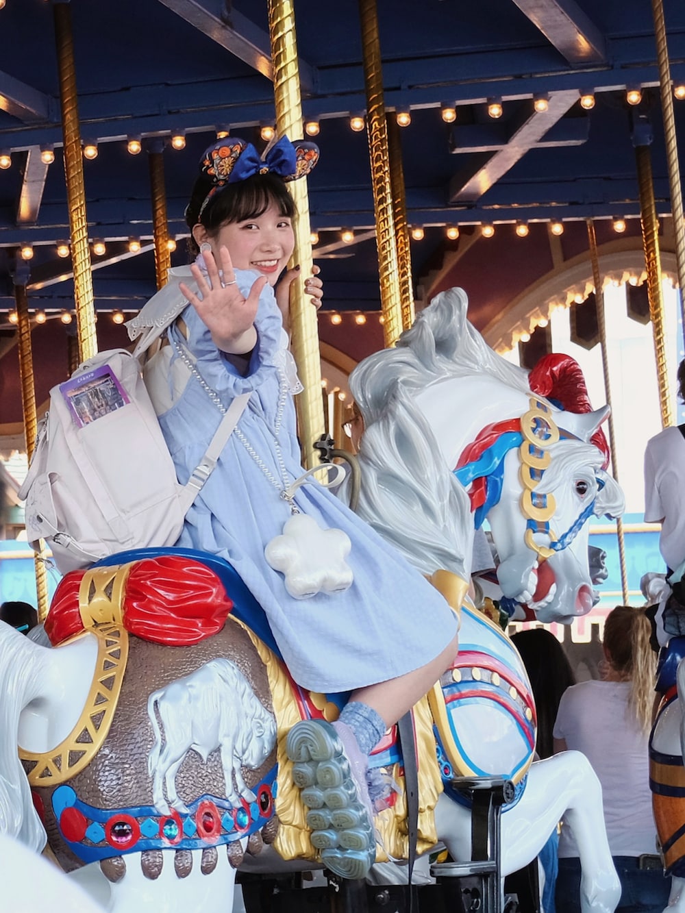 ブルー系のチュニック、ホワイト系のショルダーバッグを着用したレディースの夏コーディネートの2枚目の写真